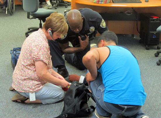 (From left) Karen McCoy, Campus Officer Kenneth Coleman and Christian Jimenez circle an unknown student who collapsed in Grossmont's library (Photo: Russ Lindquist))